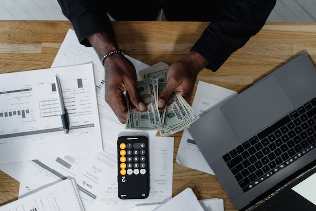 someone counting money on a table with papers and a phone